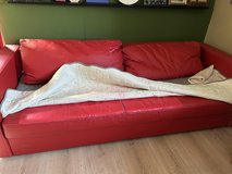 Red fake leather sofa that makes a bed, good condition except needs slipcover in Ramstein, Germany